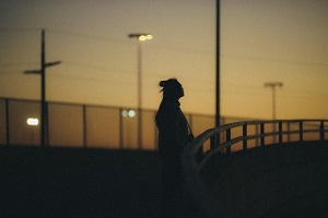 Person standing still on bridge at sunset 