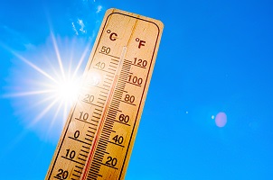 A thermometer showing how hot it is over a blue sky background