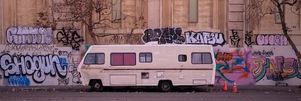 a motorhome parked in front of a graffitied building